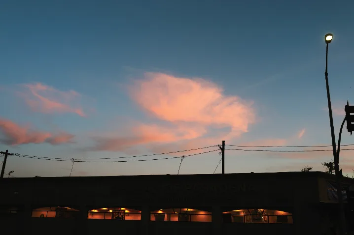 Photograph of pink clouds over a street at dusk